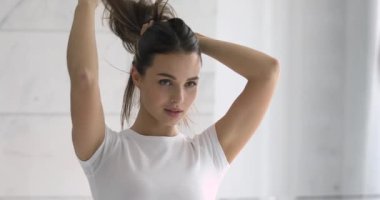 Kendine güveni tam, güzel bir kadın aynaya bakarak saçlarını yapıyor.