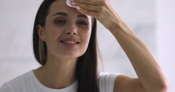 Mujer sonriente sosteniendo almohadilla de algodón limpiando la piel de la cara con limpiador — Vídeos de Stock