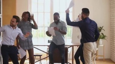 Heyecanlı çeşitli iş adamları ofiste dans eden kağıtları fırlatıyor.