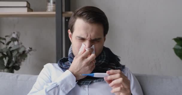 Hombre malsano sopla secreción nasal mira termómetro se siente molesto — Vídeo de stock
