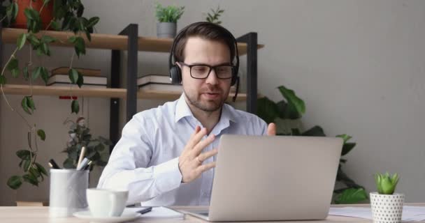 Άντρας που φοράει ακουστικά σε απευθείας σύνδεση εκπαίδευση κοιτάζοντας την οθόνη του φορητού υπολογιστή — Αρχείο Βίντεο