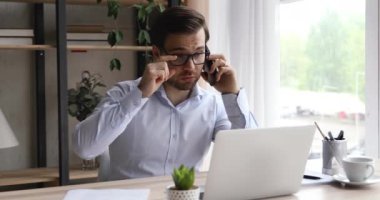 İş adamı masasında oturmuş akıllı telefonuyla müşteriyle canlı bir şekilde konuşuyor.