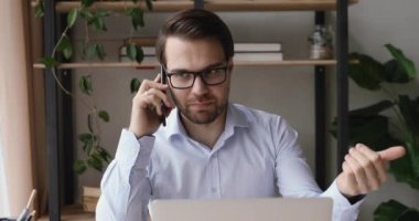 Pozitif iş adamı masada oturmuş, akıllı telefonuyla müşteriyle konuşuyor.