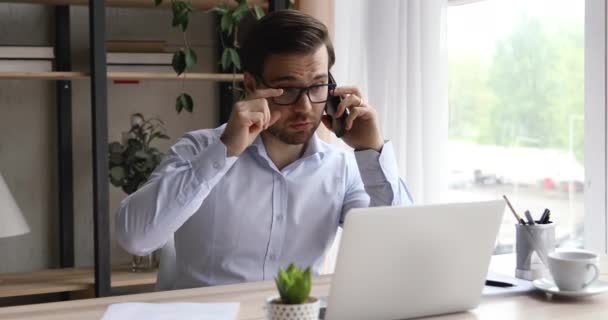 Empresario sentado en el escritorio sosteniendo teléfono inteligente hablando animado con el cliente — Vídeo de stock