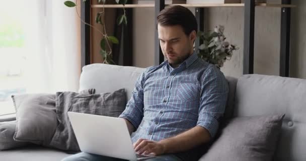 Orang yang duduk di sofa mengirim pesan balasan kepada klien menggunakan laptop — Stok Video