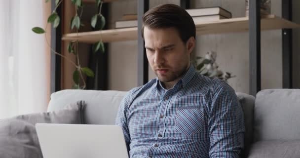 Mann, der mit Laptop sitzt und schlechte Nachrichten erhält, ist frustriert — Stockvideo
