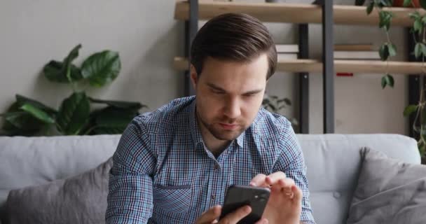 Hombre sosteniendo el teléfono celular se siente feliz por las noticias en sms recibidos — Vídeo de stock