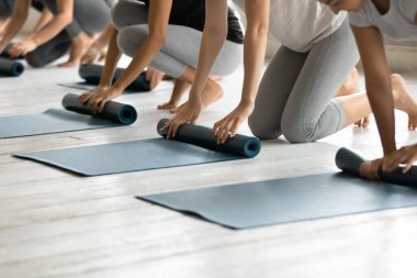 Genç, çıplak ayaklı insanlar spor paspasları katlıyor..