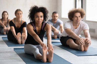 Stüdyoda grup yogasının keyfini çıkaran çok ırklı gençler..