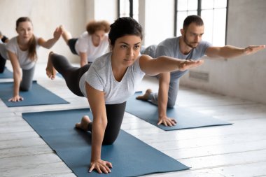 Genç Hintli antrenör yoga dersinde kuş köpek pozu veriyor..
