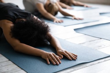 Balasana pozisyonunda uzanmış, rahat, Afro-Amerikalı bir kadın..