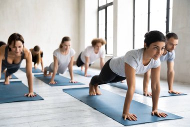 Odaklanmış genç, çok ırklı insanlar kalas pozisyonu üzerinde çalışıyorlar..