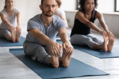 Konsantre olmuş, çok ırklı genç insanlar eğilip poz veriyorlar..