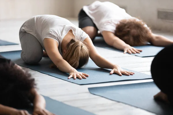 Jovem iniciante do sexo feminino deitado no tapete de chão em pose de balasana . — Fotografia de Stock