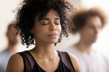 Genç, barışçıl, Afro-Amerikan kadın derin meditasyon yapıyor..