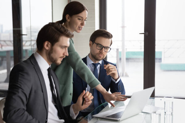 Различные сотрудники обсуждают бизнес-проект на ноутбуке в офисе
