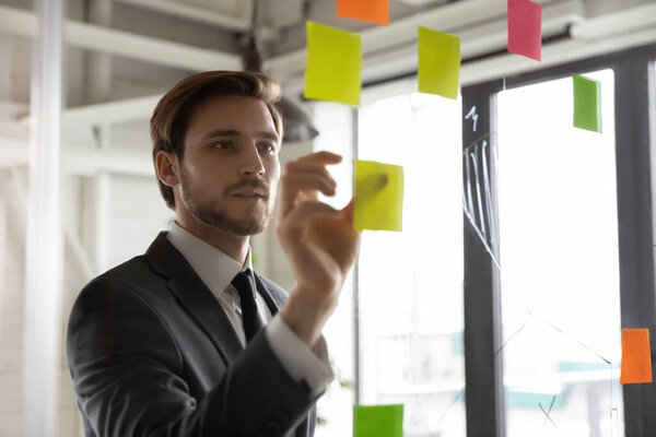 Focused male employee work with sticky notes develop business plan