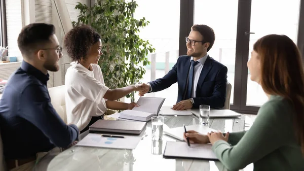 Smiling multiethnic businesspeople handshake at team office briefing — Stock Photo, Image