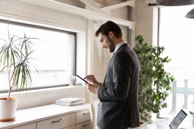 Genç Kafkasyalı işadamı ofiste akıllı telefon kullanıyor.