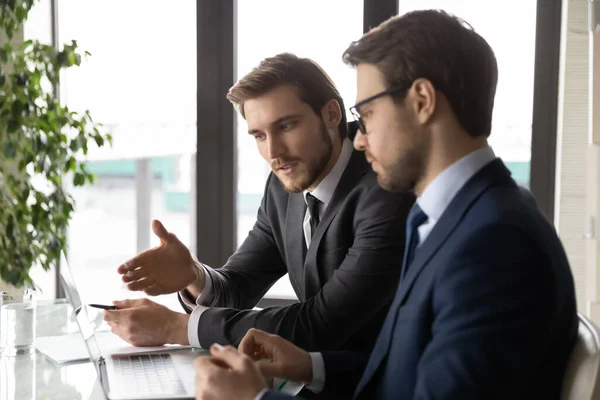 Los empresarios caucásicos miran la pantalla del ordenador portátil discutiendo ideas —  Fotos de Stock