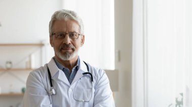 Beyaz üniformalı yaşlı bir erkek doktorun profil fotoğrafı.