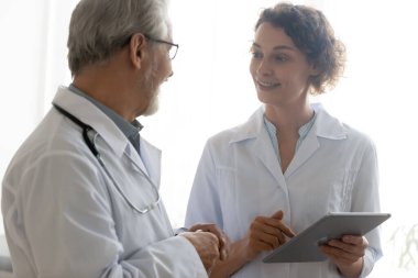 Gülümseyen çeşitli doktorlar konuyu tablet kullanarak tartışıyor