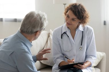 Gülümseyen kadın hemşire yaşlı erkek hastaya danışıyor