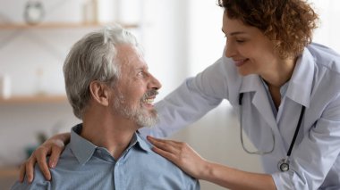 Gülümseyen kadın hemşire kıdemli hastayı destekliyor.