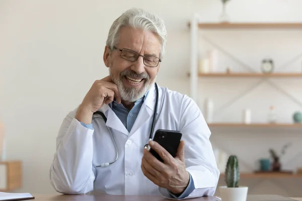 Sonriente médico masculino senior consultar paciente en el teléfono celular — Foto de Stock