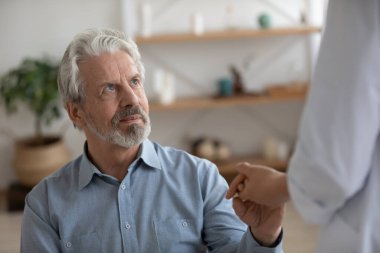 Bakıcı kadın hemşire hastanede yaşlı adama destek oluyor.