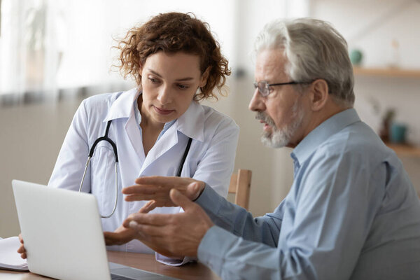 Female doctor consult elderly male patient at hospital