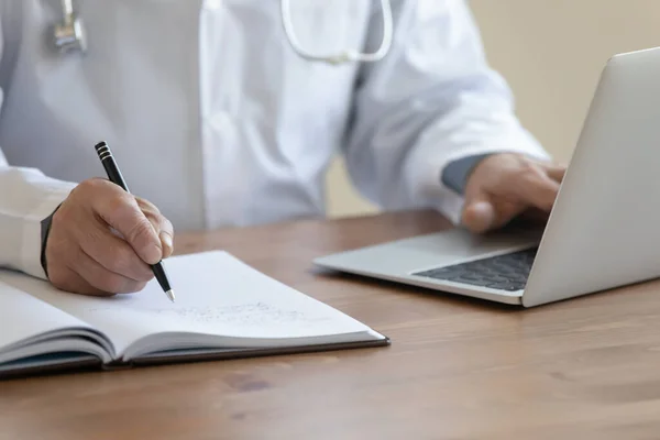 Close up of male doctor work on computer making notes — Stock Photo, Image