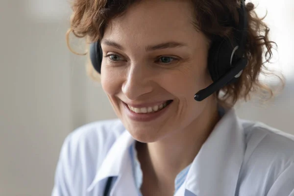 Smiling female doctor in headset consult patient online