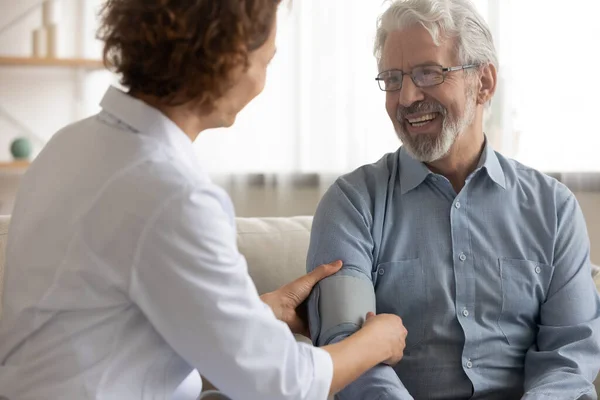 Pflegende Krankenschwester misst Blutdruck einer Seniorin — Stockfoto