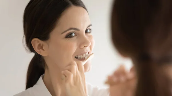 Close up mirror reflection woman with healthy smile cleansing teeth