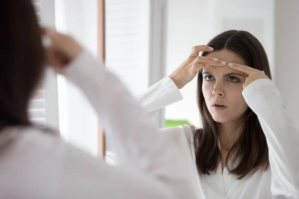 Head shot mirror reflection unhappy woman squeeze pimple on forehead — Stock Photo, Image