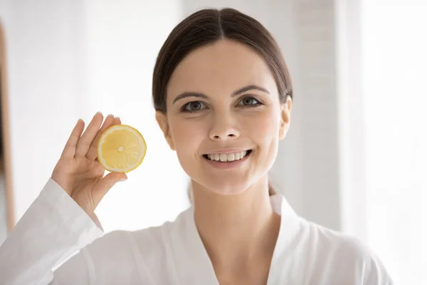 Head shot portrait woman with healthy smile holding lemon