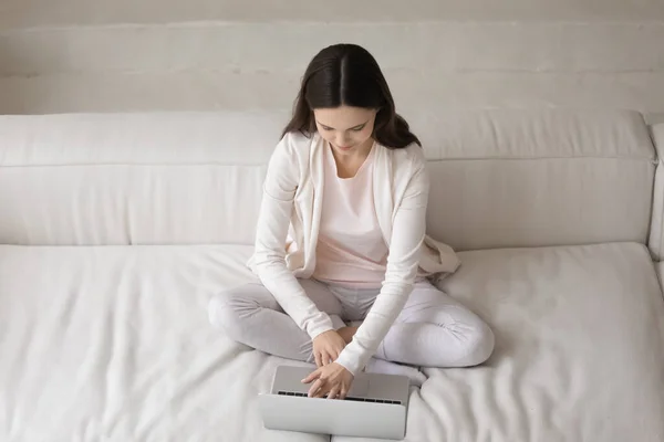 Top view jonge vrouw met behulp van laptop, zitten op gezellige bank — Stockfoto