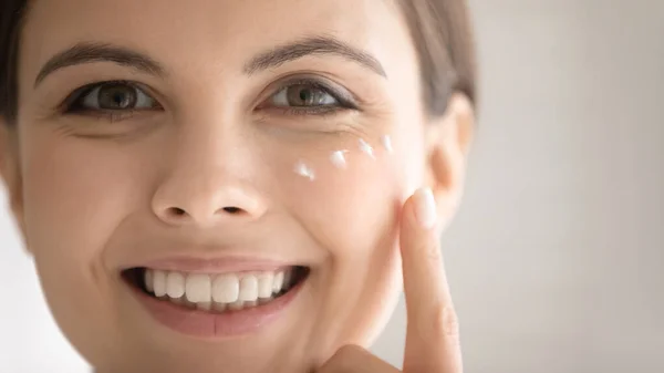Close up sorridente bella donna applicare crema idratante per il viso — Foto Stock