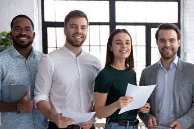 Çeşitli iş adamları kameraya bakarak ofiste poz veriyor.