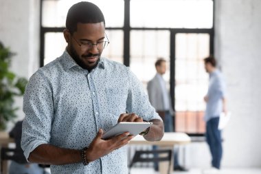 Konsantre olmuş Afrikalı işadamı elektronik tablet üzerine sunum hazırlıyor