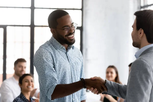 African employee got promotion feels happy shake hands with boss