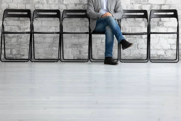 Nierozpoznany mężczyzna siedzi na krześle i czeka na rozmowę kwalifikacyjną. — Zdjęcie stockowe