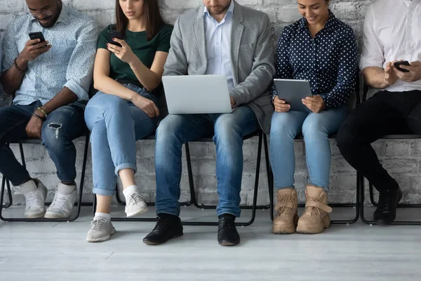 Group of young people sitting on chairs with electronic gadgets — Stock Photo, Image