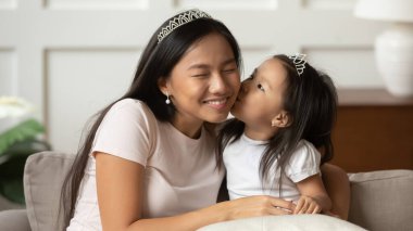 Küçük komik Vietnamlı etnik kız annesini öpüyor..