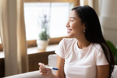 Hamilelik testi tutan Asyalı bir kadın..