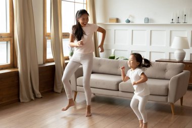 Enerjik genç Vietnamlı etnik anne küçük kızıyla dans ediyor..