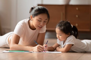 Vietnamlı etnik kadın küçük çocukla resim çiziyor.