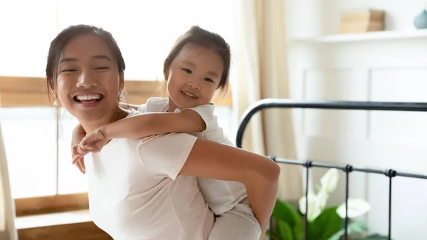 Sorridente giovane madre vietnamita che dà cavalcata al bambino felice. — Foto Stock