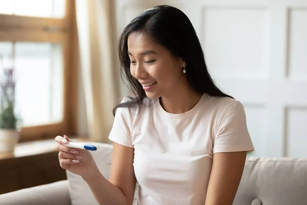Attractive vietnamese ethnicity woman looking at pregnancy test. — Stock Photo, Image
